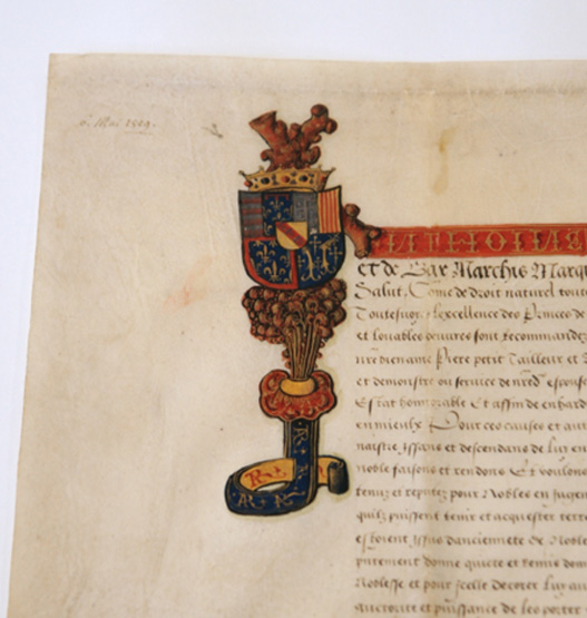  Ornate drop capital letter decorated with a crown and vivid coats of arms on a historical manuscript page.<br />