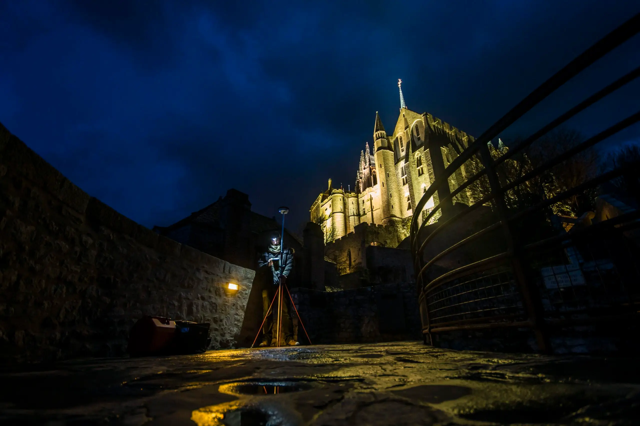 A technician setting up a camera and laser scanning equipment for comprehensive architectural surveys at Mont-Saint-Michel Abbey.