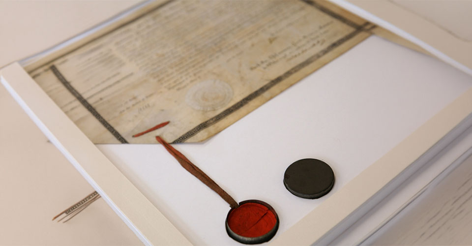 Bespoke conservation housing protecting a fragile red wax seal set inside a small tin box alongside a historical document