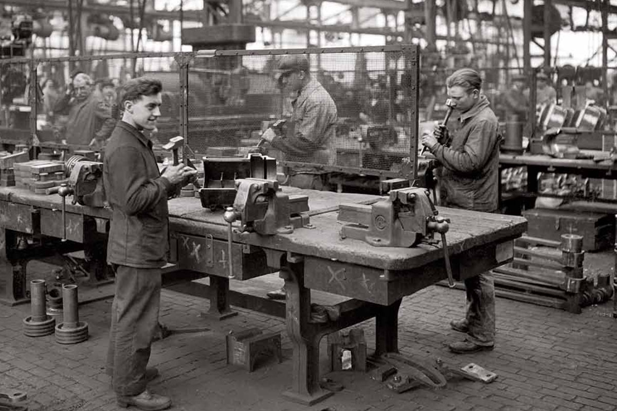 Ouvriers travaillant autour d’établis équipés d’étaux dans l’atelier de chaudronnerie de Fives-Lille en 1933.