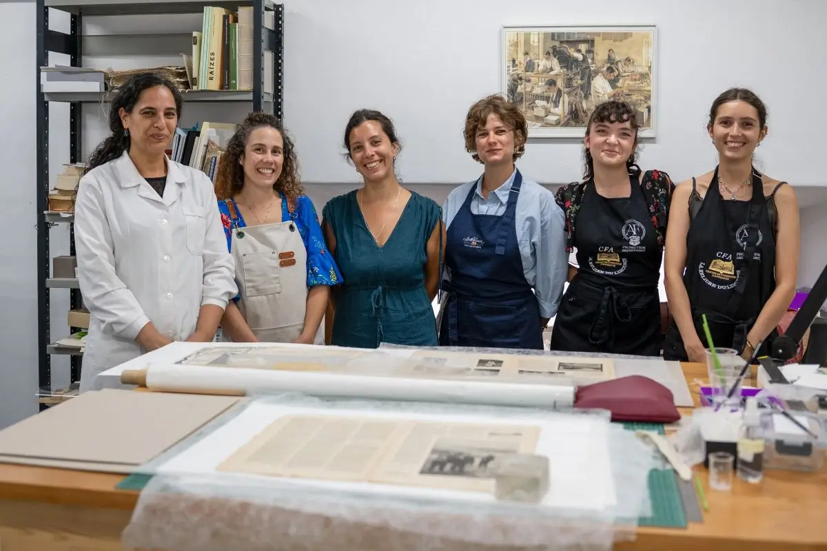 MEMORIST CFA apprentices and University of Coimbra conservators standing in a paper restoration studio.